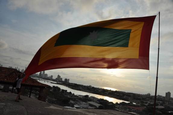 Brigando com o vento e com a enorme bandeira de Cartagena, no alto do Castillo San Felipe, em Cartagena, na Colômbia